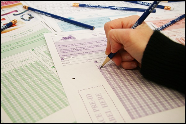 Hand holding a pencil on a scantron sheet